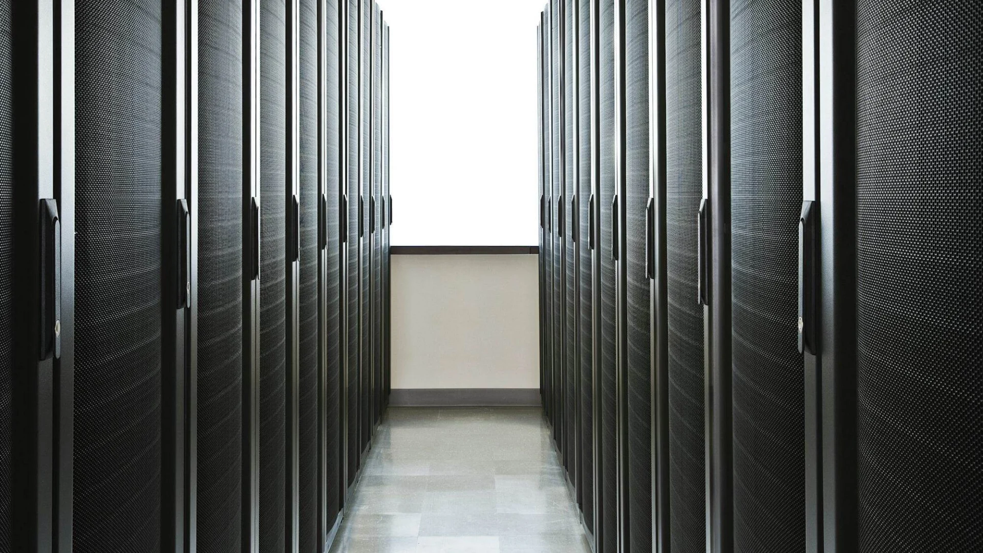 Storage racks aligned in a computer server room with a large window in the background.